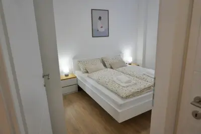 a small bedroom with a white bed with two lamps at Apartman Anita in Kupres