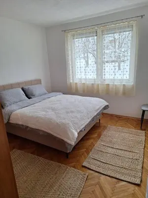 a bedroom with a bed and two rugs in front of a window at Apartman Centar in Drvar