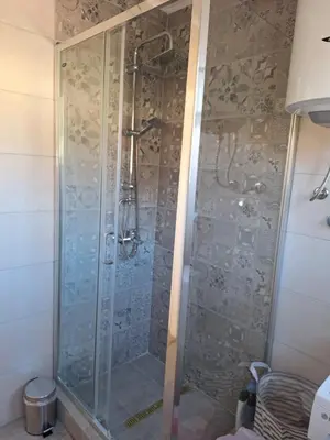 a shower with a glass door in a bathroom at Apartman Centar in Drvar