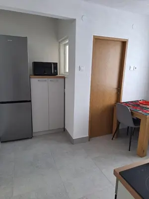 a room with a kitchen with a refrigerator and a table at Apartman Centar in Drvar