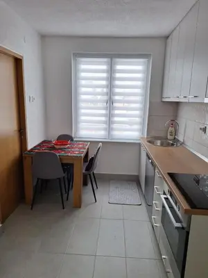 a kitchen with a table with chairs and a window at Apartman Centar in Drvar