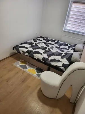 a bedroom with a bed and a chair and a rug at Apartman Magi in Prnjavor