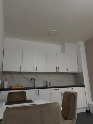 a kitchen with white cabinets and a sink and a chair at Apartment Lofty Dreams in Banja Luka