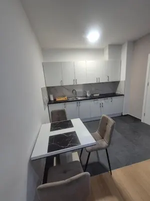 a kitchen with white cabinets and a table and chairs at Apartment Lofty Dreams in Banja Luka
