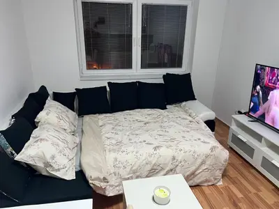 a black couch in a living room with a bed at Apartman Ivano Kupres in Kupres