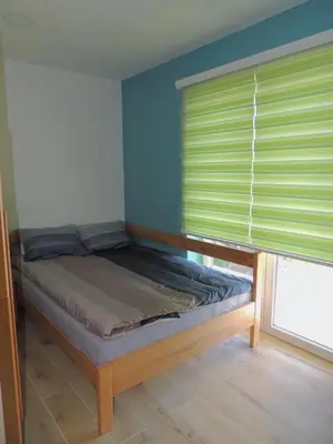 a bed in a room with a window with green blinds at Hostel Sobe Popović in Nova Bila