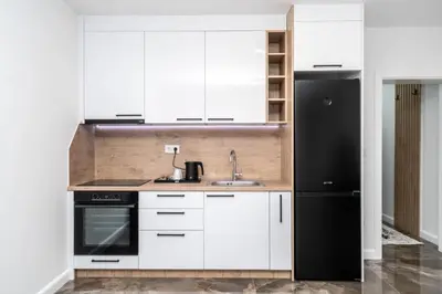 a kitchen with white cabinets and a black refrigerator at Apartmani Deluxe in Sanski most