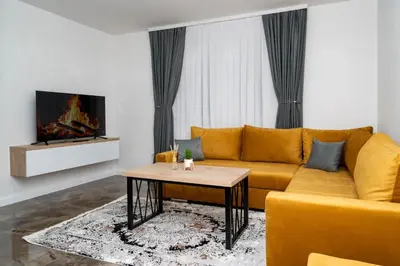 a living room with a yellow couch and a coffee table at Apartmani Deluxe in Sanski most