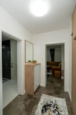 a living room with white walls and a bathroom at Apartmani Deluxe in Sanski most