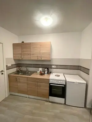 a kitchen with wooden cabinets and a white stove top oven at Studio 34 in Doboj