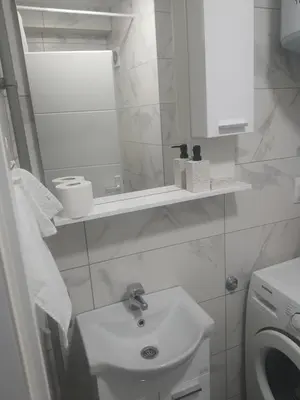 a white bathroom with a sink and a washing machine at Apartman Bato in Banja Luka