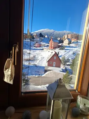 a view of a snow covered village from a window at Apartman Montis in Kupres
