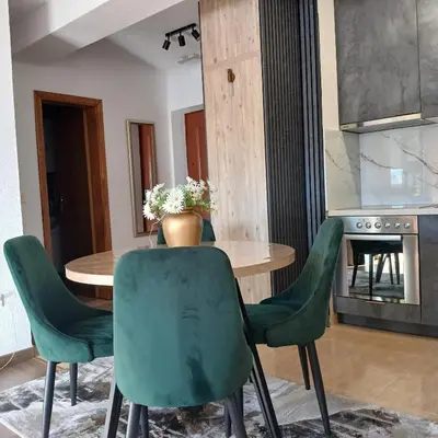 a dining room with a table and green chairs at Apartman Montis in Kupres