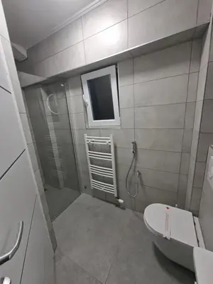 a bathroom with a shower and a toilet and a window at Pansion Kod Brajlovica in Tuzla
