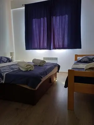 a bedroom with two beds and a window with purple curtains at Ugodan Kutak in Kupres