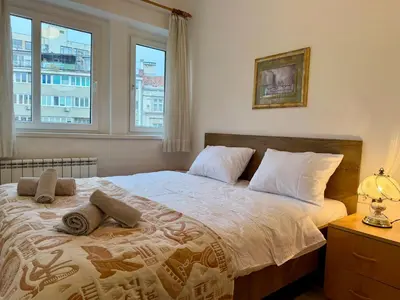 a bedroom with a large bed with two windows at Apartments by BENCO in Ivišovo Greblje