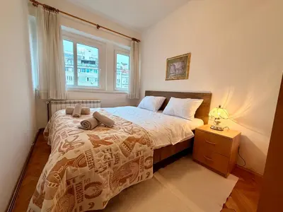 a bedroom with a bed with a night stand and a window at Apartments by BENCO in Ivišovo Greblje