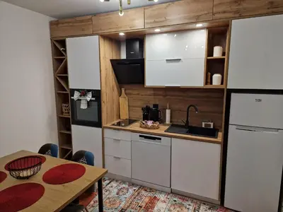a kitchen with white cabinets and a table with a tableablish at Apartman Miki in Vlasic