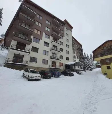 a snow covered parking lot in front of a building at Apartman Miki in Vlasic