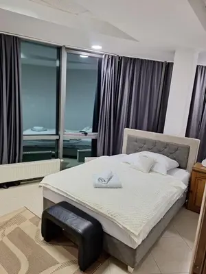 a bedroom with a large bed with a black ottoman at Prenoćište Durić in Cazin
