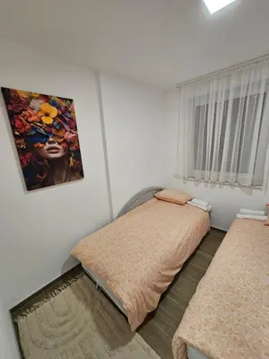 a bedroom with two beds and a painting on the wall at Apartman IVA in Modriča