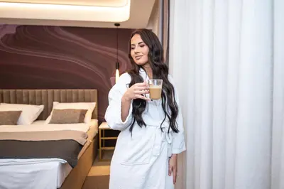 a woman holding a cup of coffee in a bedroom at Hotel Story in Žepče