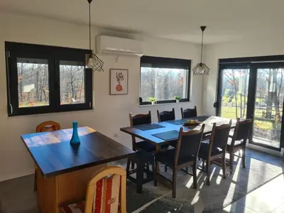a dining room with a table and chairs and windows at Villa Aria in Bosanska Krupa