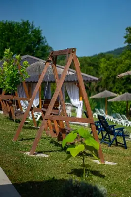 a wooden swing set in a yard with chairs and umbrellas at Una Relax in Vajagići