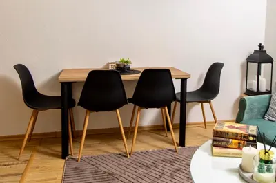 a dining room table with four black chairs around it at SkyLux Vlašić in Šišava