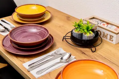 a wooden table with plates and bowls and a potted plant at SkyLux Vlašić in Šišava