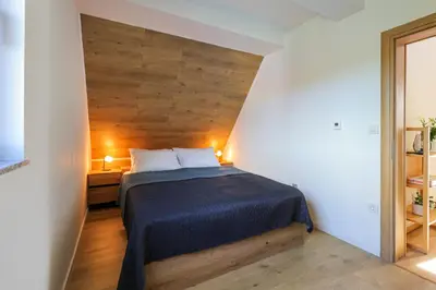 a bedroom with a bed with a wooden wall at Viva Vlasic - Apartman i vikendica in Šišava