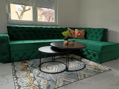 a green couch in a living room with a table at SPA APARTMAN Prijedor in Prijedor