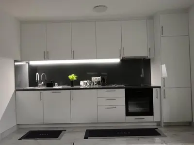 a kitchen with white cabinets and a black and white appliances at SPA APARTMAN Prijedor in Prijedor