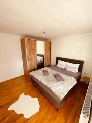 a bedroom with a bed and a laptop on a wooden floor at Apartman Šimić in Kupres