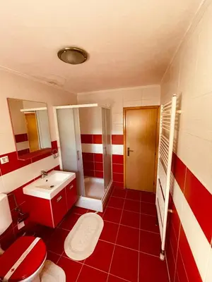 a red and white bathroom with a toilet and a sink at Apartman Šimić in Kupres