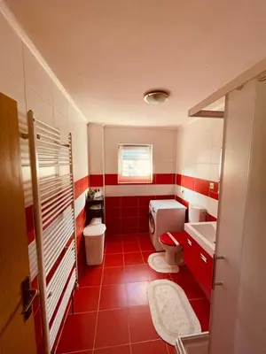 a red and white bathroom with a toilet and a sink at Apartman Šimić in Kupres