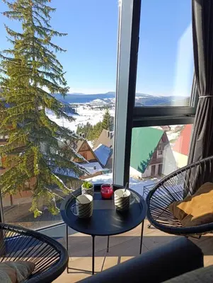 a balcony with a table and chairs and a tree at Vlašić Grand View in Vlasic