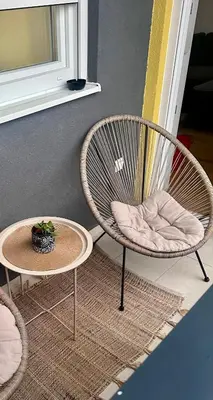 a rattan chair and a table with a plant on it at Sky View - Apartment & GARAGE, Banja Luka in Banja Luka