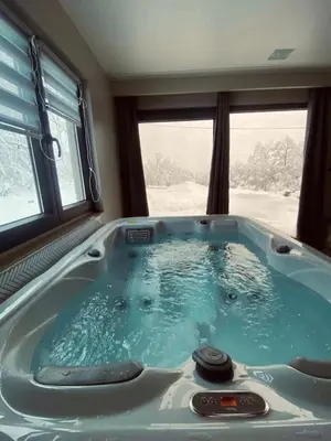 a jacuzzi tub in a room with two windows at Relax house - Šumska vila romanticni spa apartman sa djakuzijem in Banja Luka