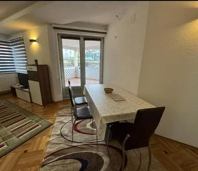a living room with a table and chairs and a window at Golden Lilly Apartment in Bihać