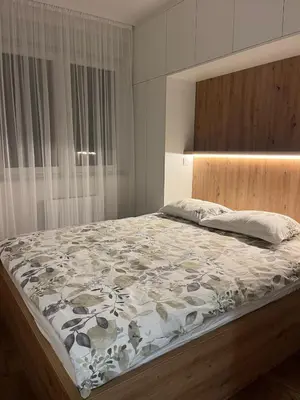 a bedroom with a large bed with a wooden headboard at Aurelia Apartmani - Banja Luka-Borik in Banja Luka