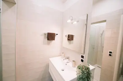 a white bathroom with a sink and a mirror at Studio apartman NINA in Livno
