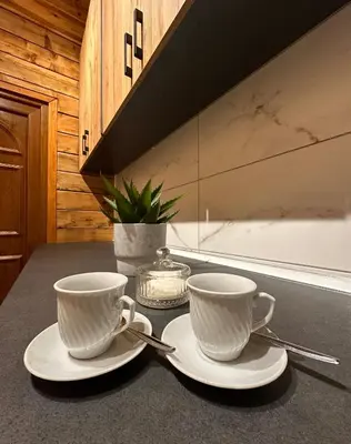 two white cups and saucers on a kitchen counter at Green District - Riverside Luxury Lodge in Banja Luka