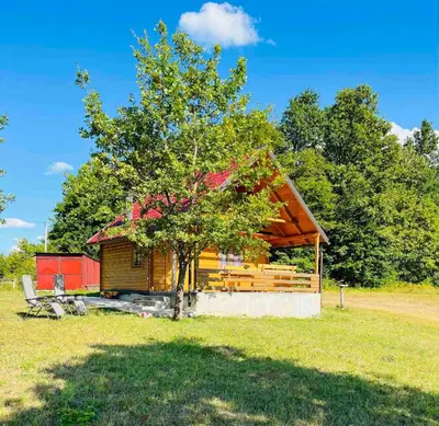 a log cabin with a tree in a field at Brvnara Duga njiva Banjaluka in Čelinac