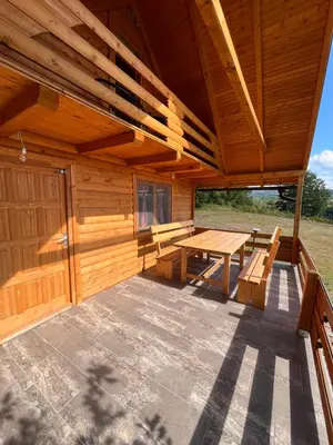 a wooden cabin with a picnic table and benches at Brvnara Duga njiva Banjaluka in Čelinac