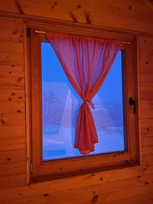 a window in a wooden room with a red curtain at Brvnara Duga njiva Banjaluka in Čelinac