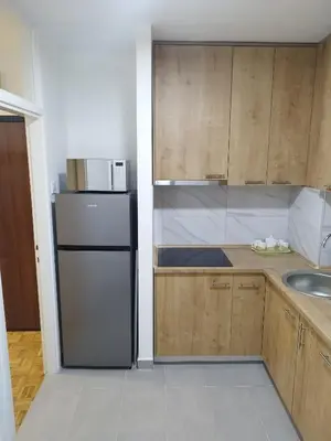 a kitchen with a black refrigerator and wooden cabinets at Apartman Harmony N&D in Starčevica