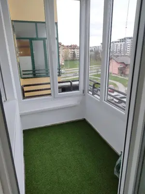 a room with two windows and a green floor at Apartman Harmony N&D in Starčevica