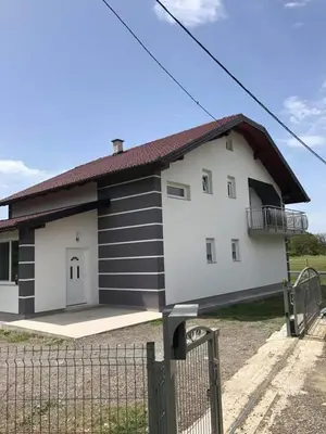 a large white and black building with a fence at Sobe DANA in Teslić