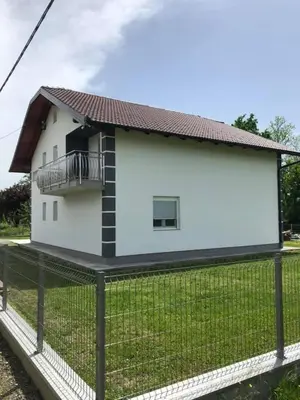 a white house with a balcony on top of a fence at Sobe DANA in Teslić